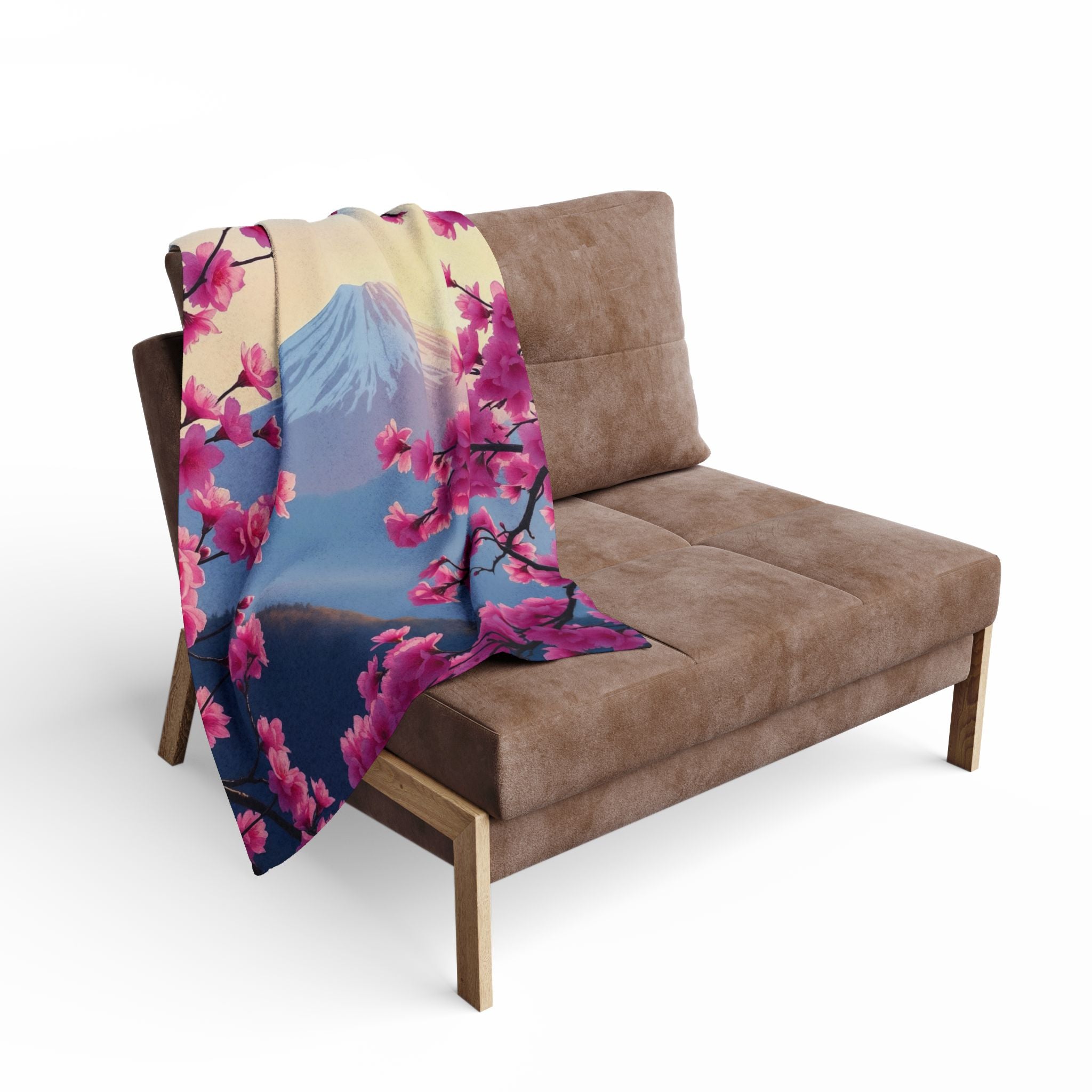 Sofa with a pink cherry blossom and mountain design fleece blanket draped over it on a white background.