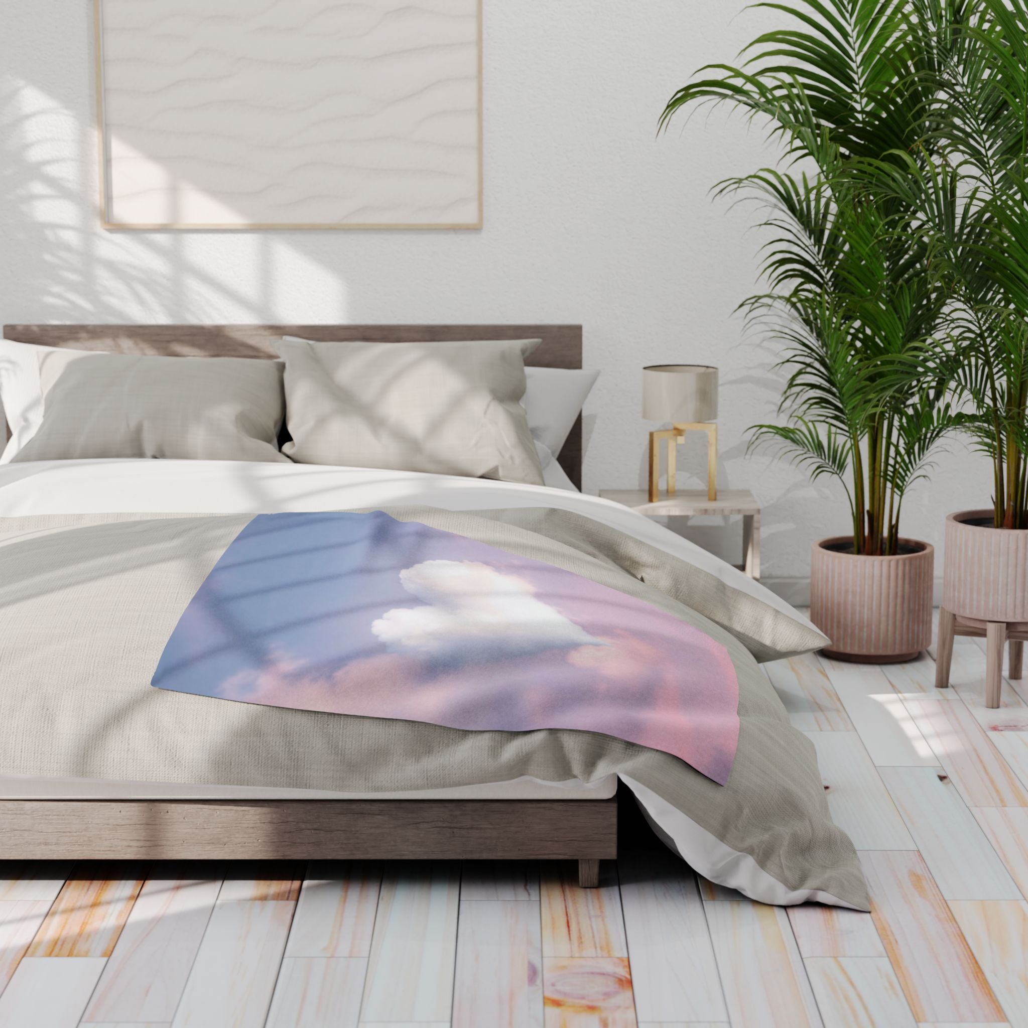Bedroom with a bed featuring a blanket with a heart shaped cloud on a blue and pink sky, nightstands, and a plant.