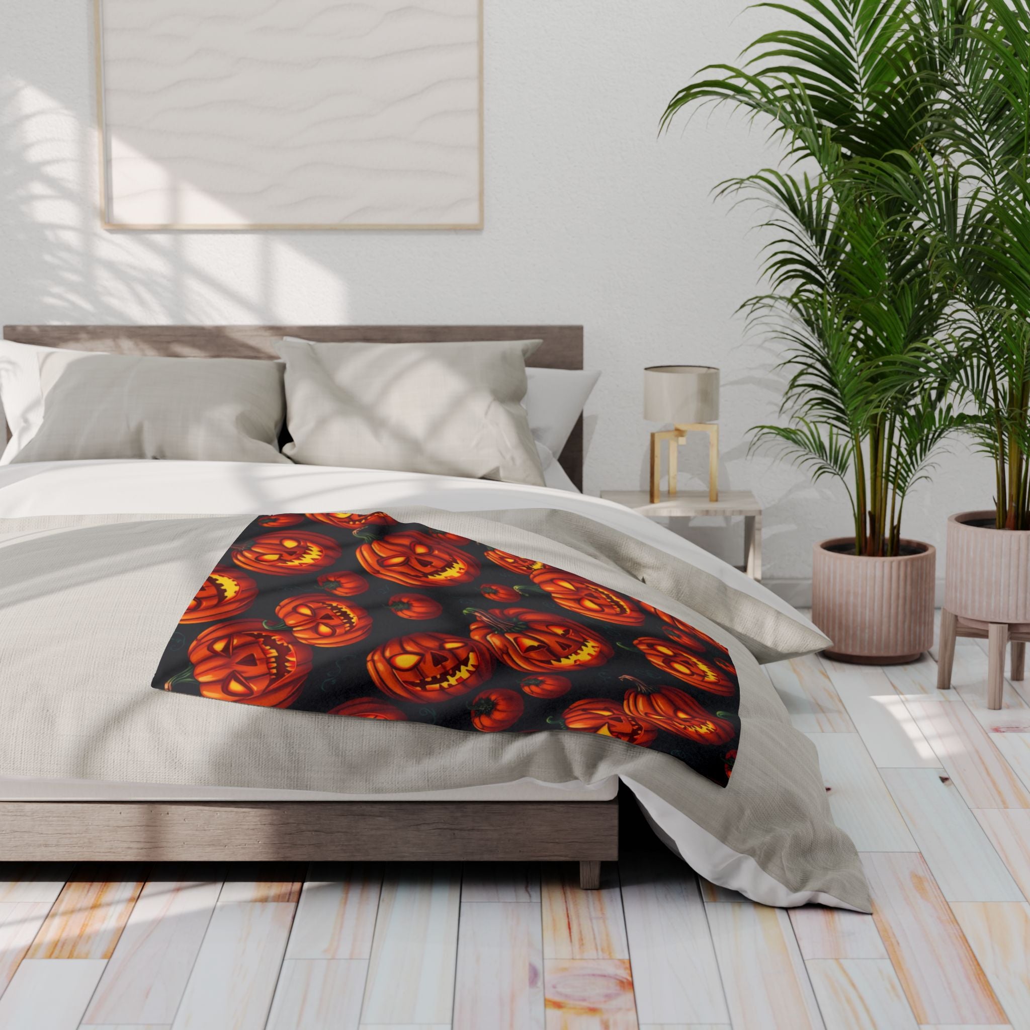 Bed with a halloween pumpkin patterned fleece blanket in a modern bedroom setting.