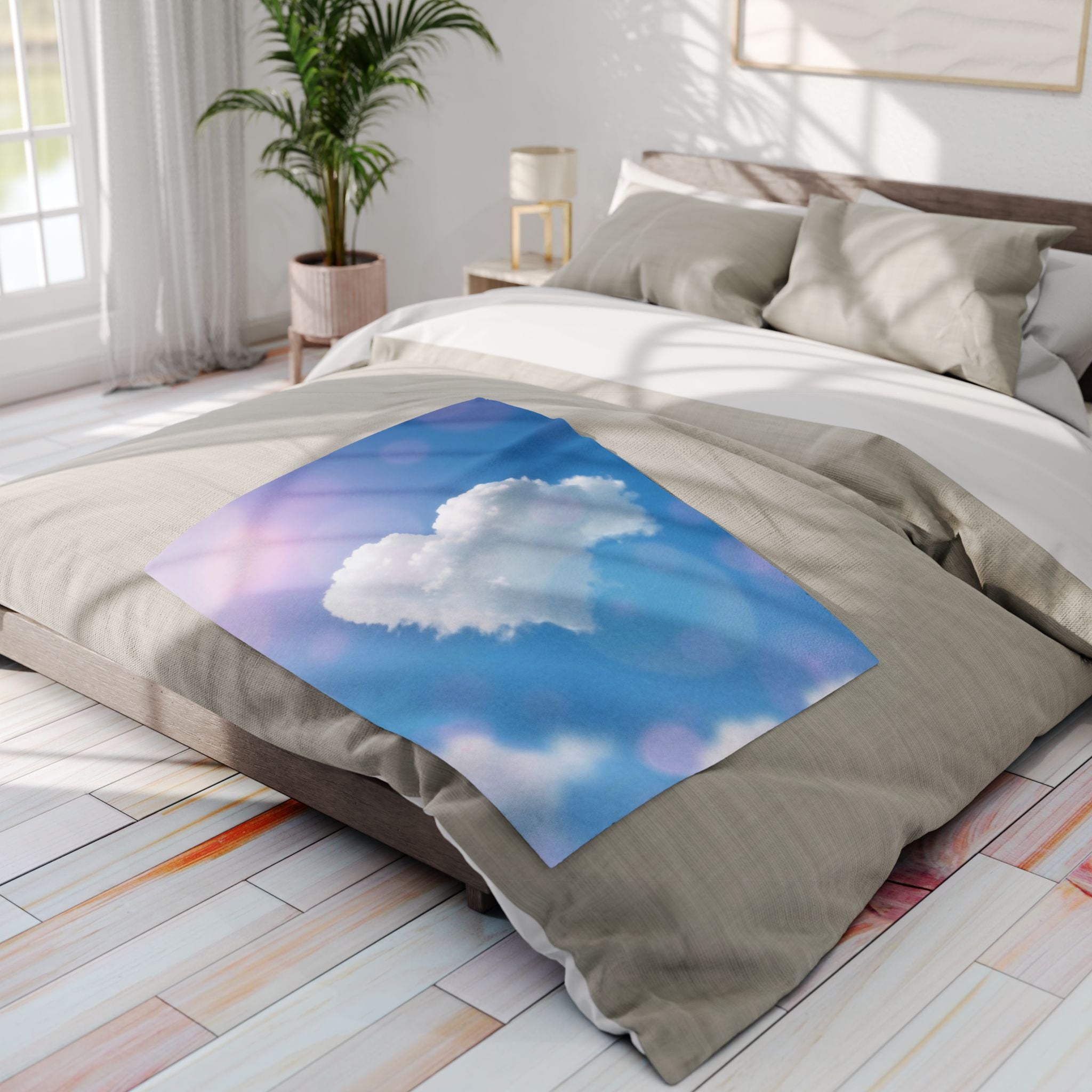 Bed featuring a fleece blanket with a white heart cloud on a blue sky fleece in a bright bedroom.