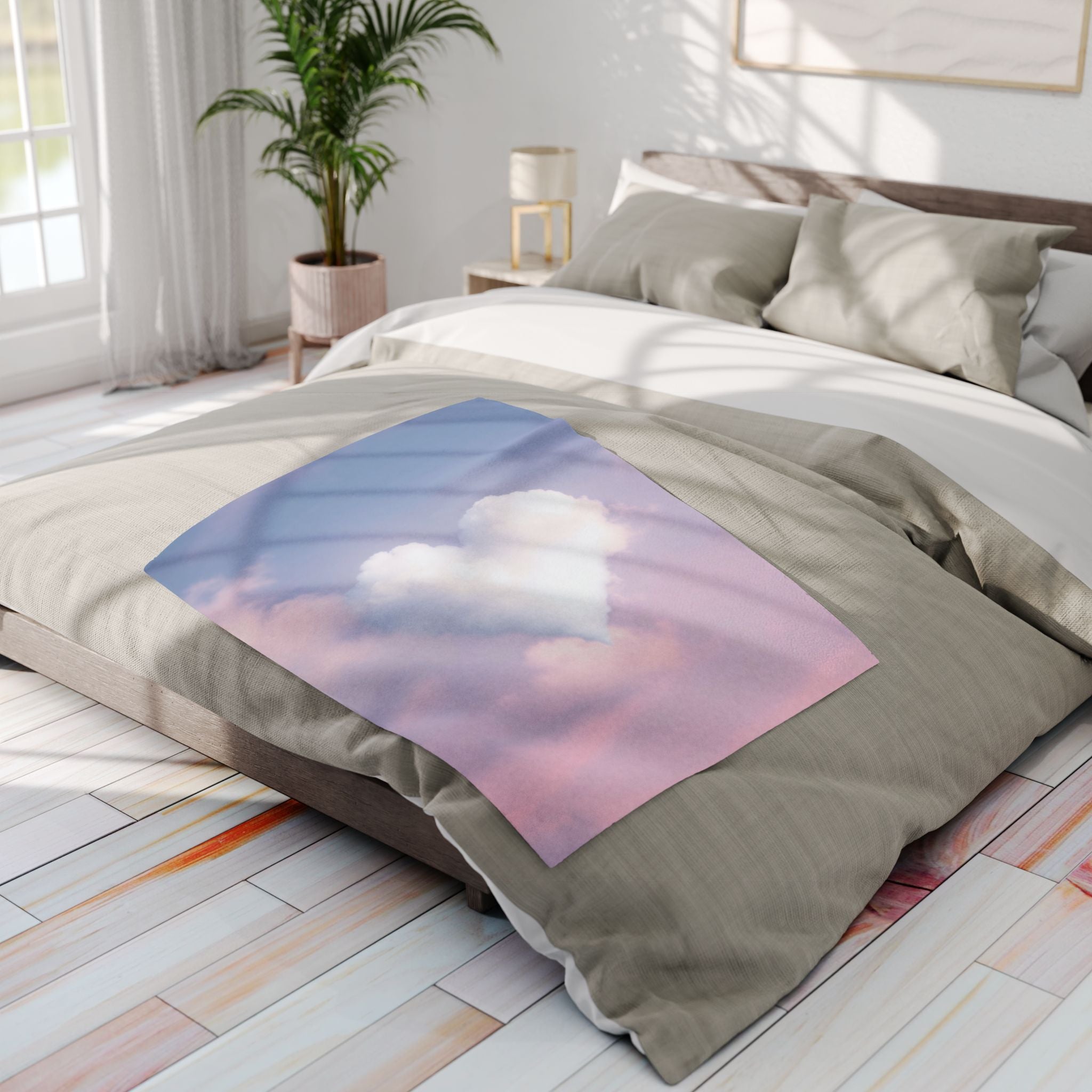 Bed with a decorative fleece blanket featuring a heart shaped cloud design in a bright bedroom.