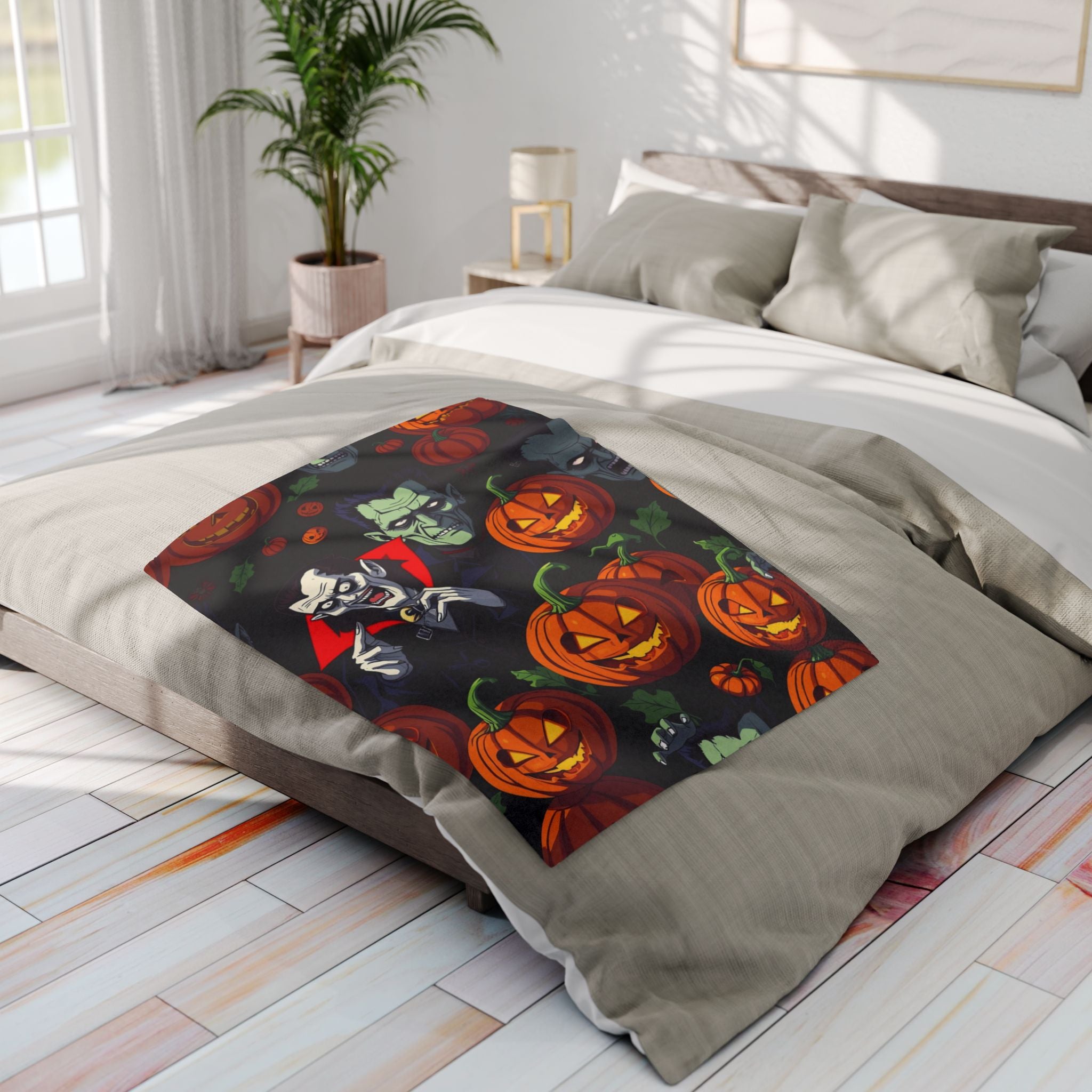 Halloween themed decorative fleece blanket featuring Dracula, Frankenstein and pumpkin lanterns on a bed in a bright bedroom.