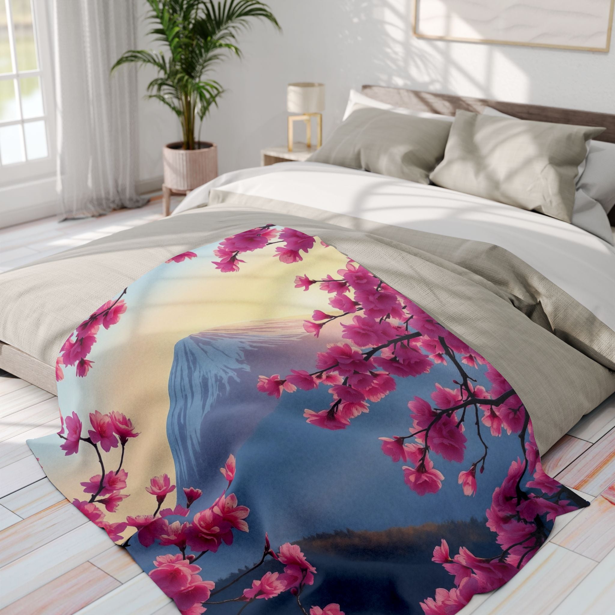 Decorative fleece blanket with pink cherry blossom and mount fuji design on a bed in a bright bedroom.