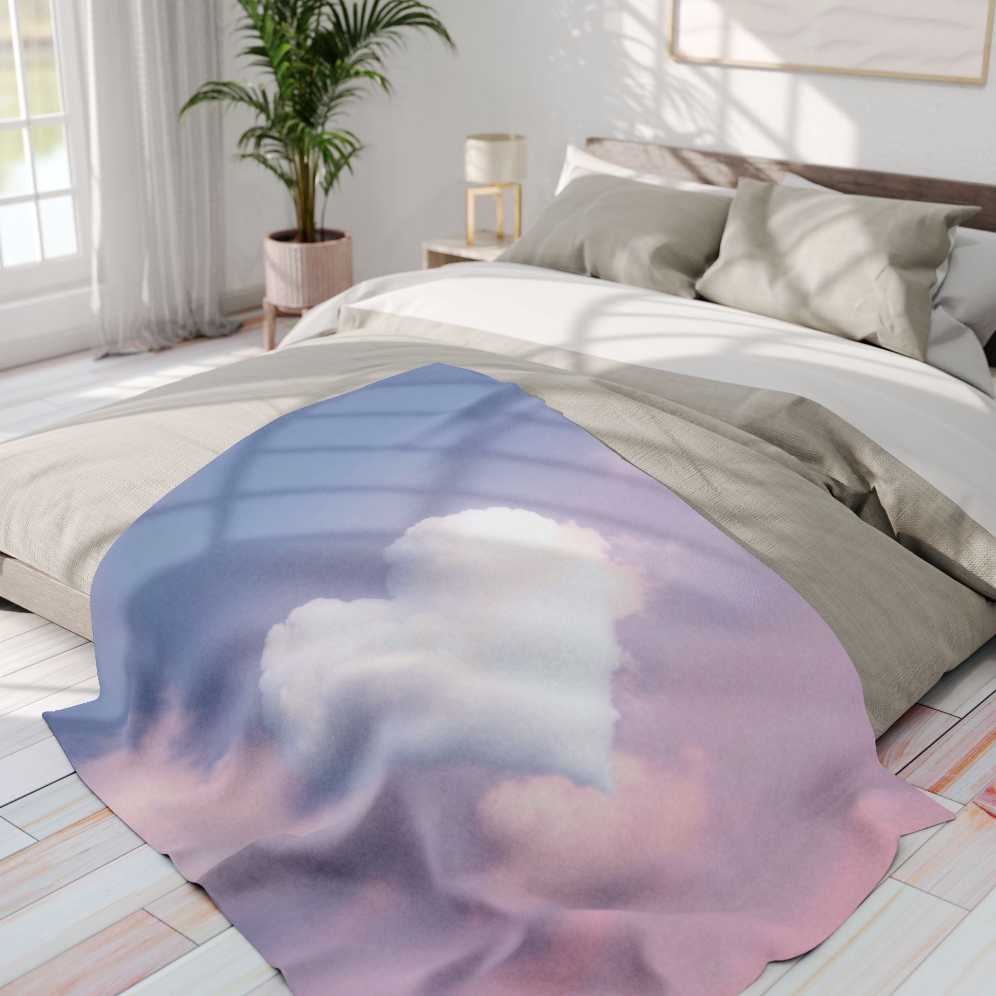 Bed with a heart shaped cloud on a blue and pink sky fleece blanket in a bright bedroom.
