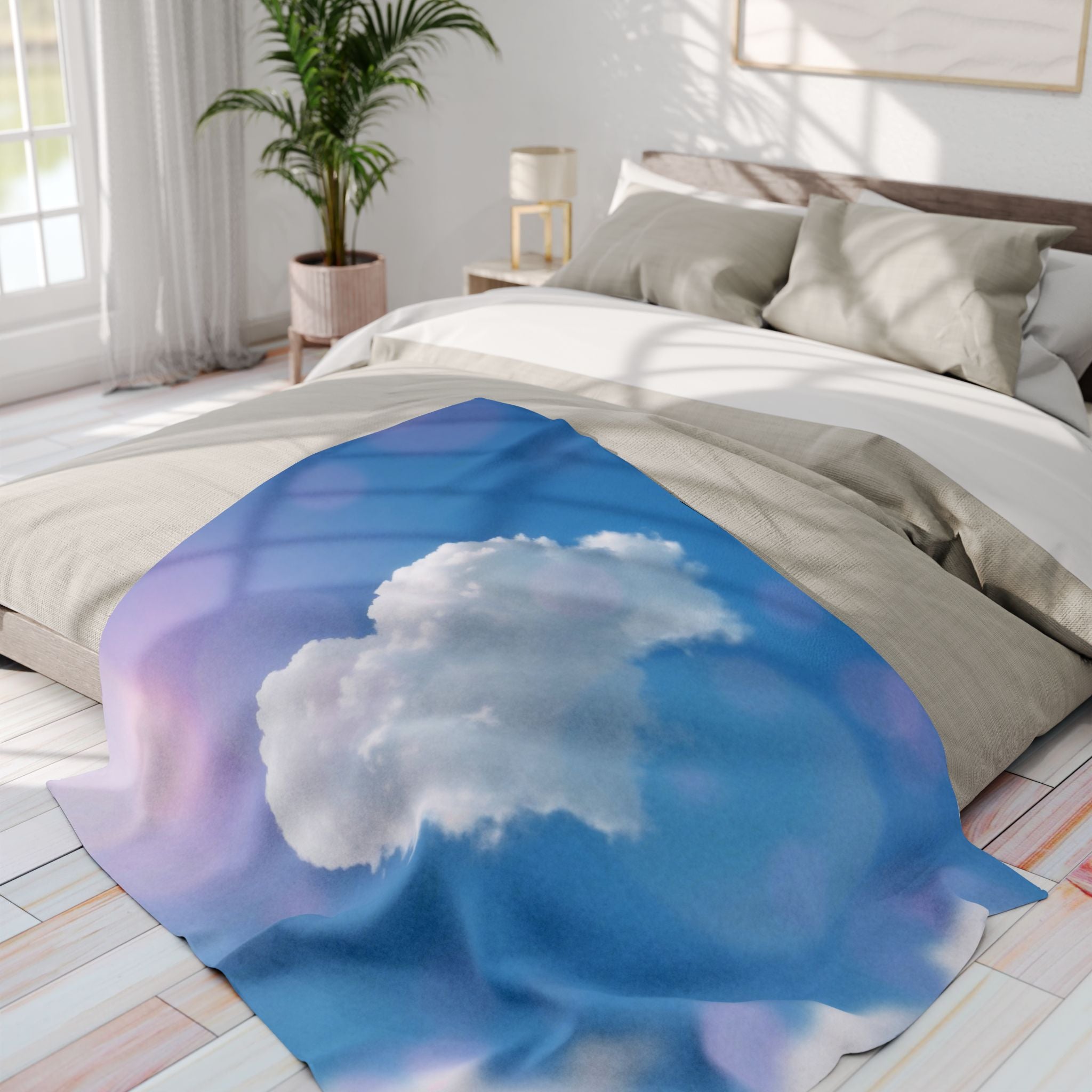 Bed with a white heart cloud on a blue and purple sky fleece blanket in a bright bedroom.