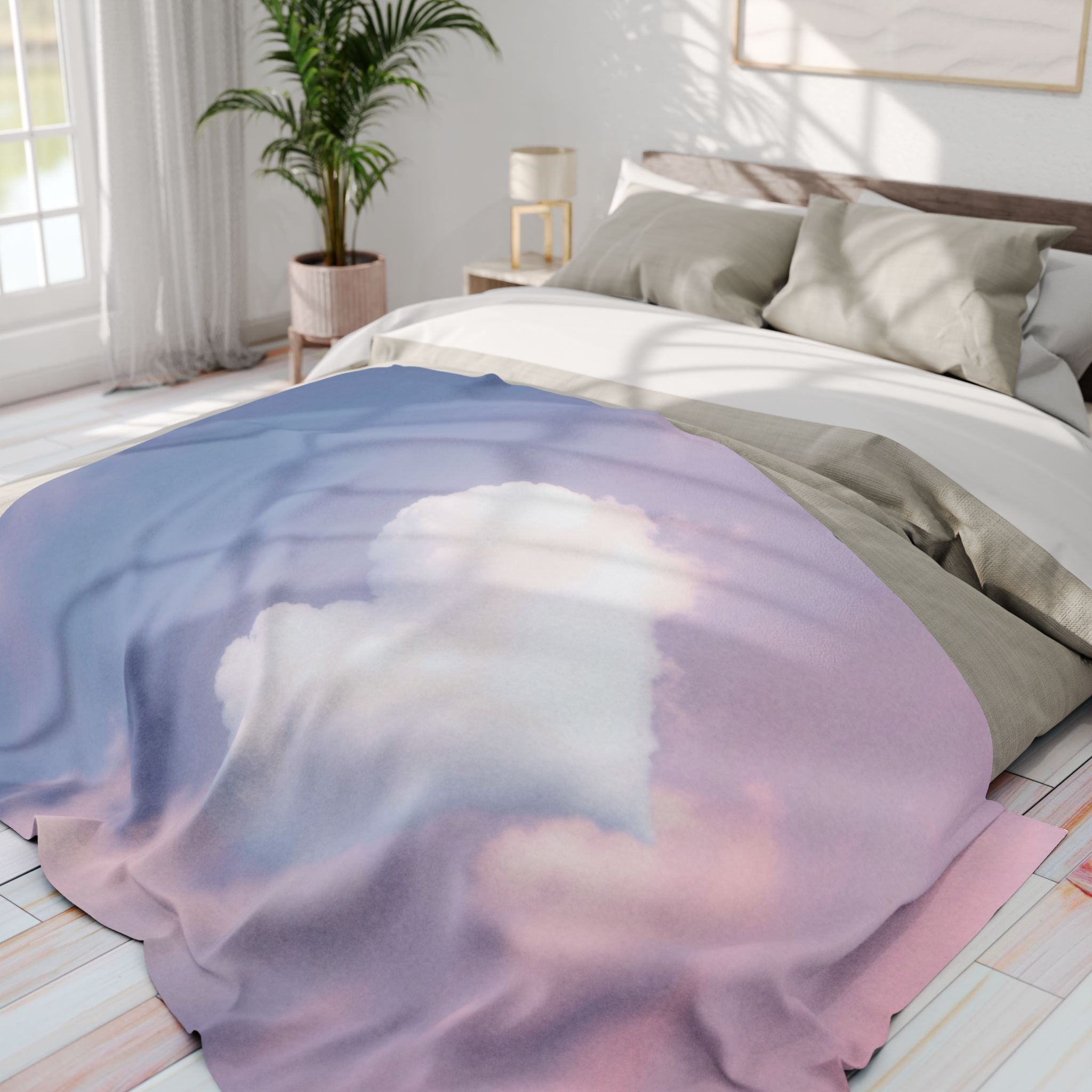 Bed with a heart cloud on a pink and blue sky fleece blanket draped over it in a bright bedroom.