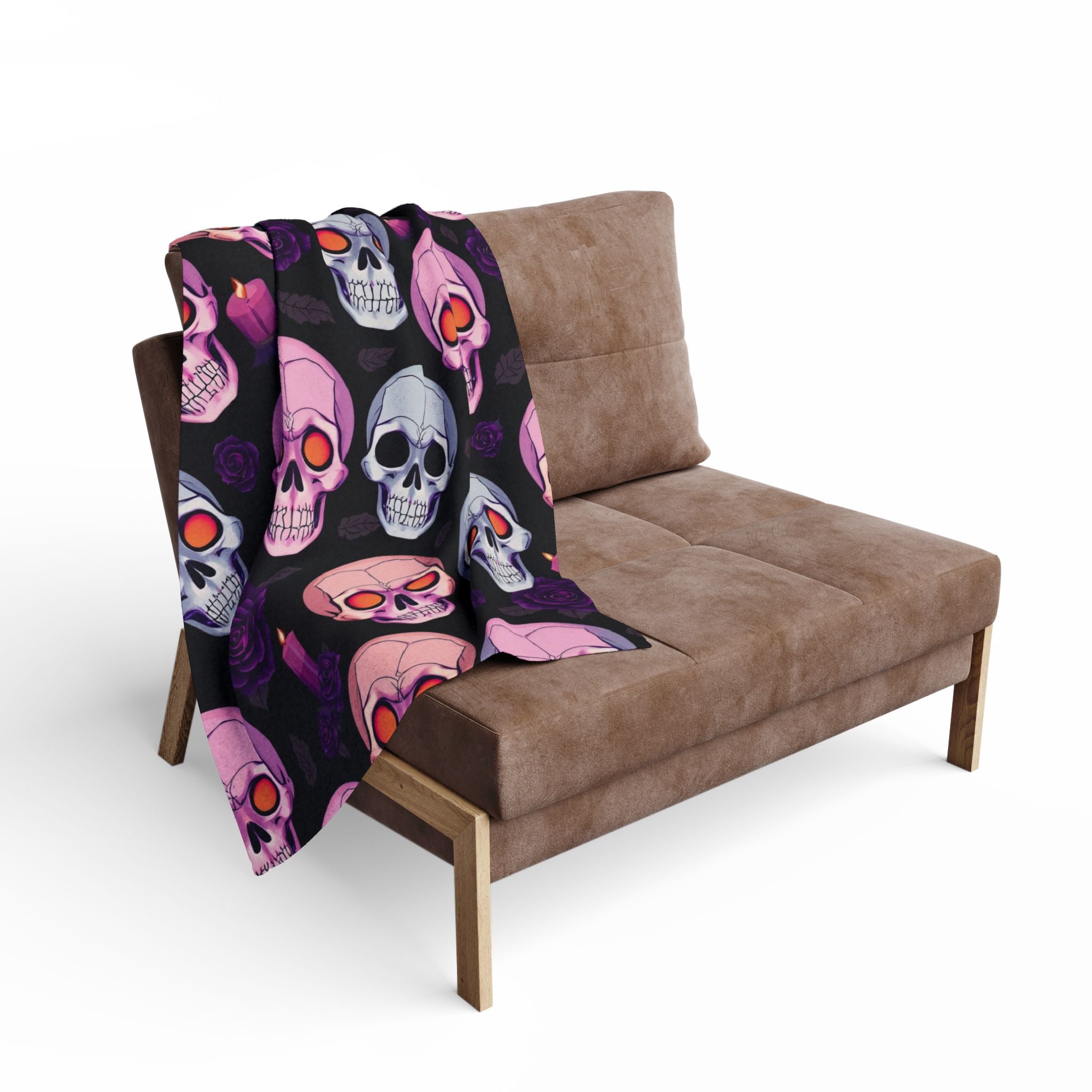 Skull patterned Halloween fleece blanket draped over a brown sofa on a white background.