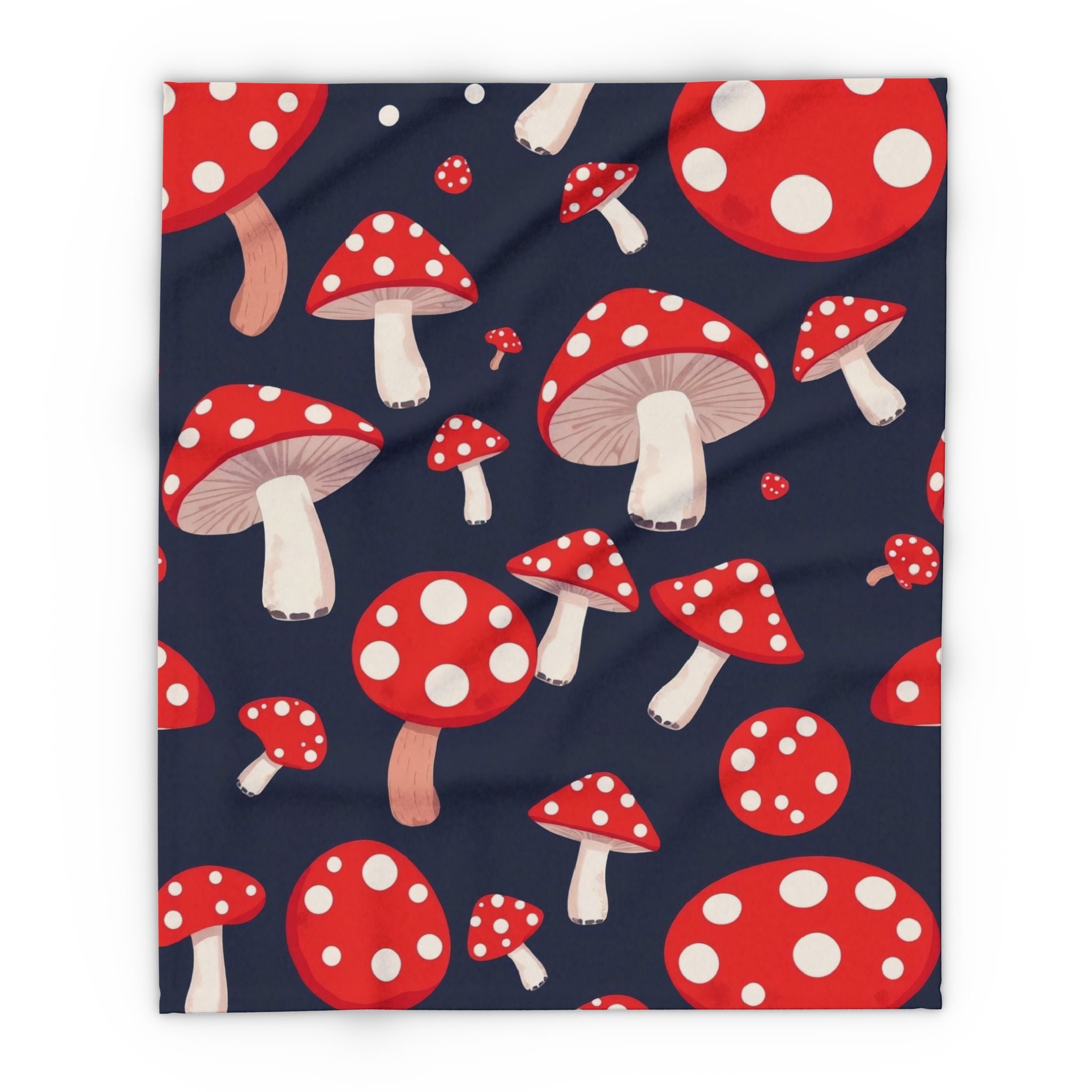Fleece blanket throw featuring a pattern of red and white spotted mushrooms on a dark blue background.